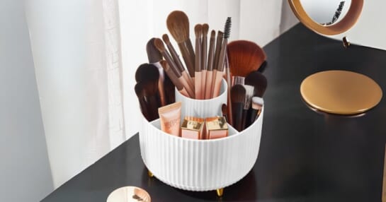 white and gold Rotating Makeup Brush Organizer with makeup brushes and makeup in it