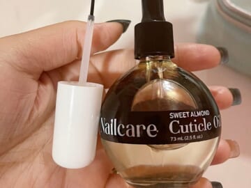hand holding care c sweet almond cuticle oil bottle with brush