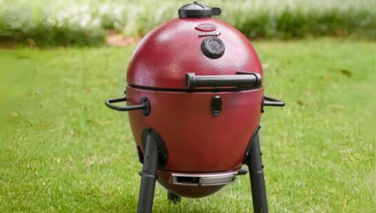 a red kamado grill in a grassy backyard