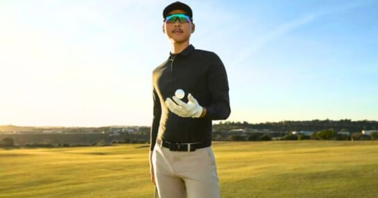 man on a green wearing lululemon golf clothing while holding a golf ball and golf club